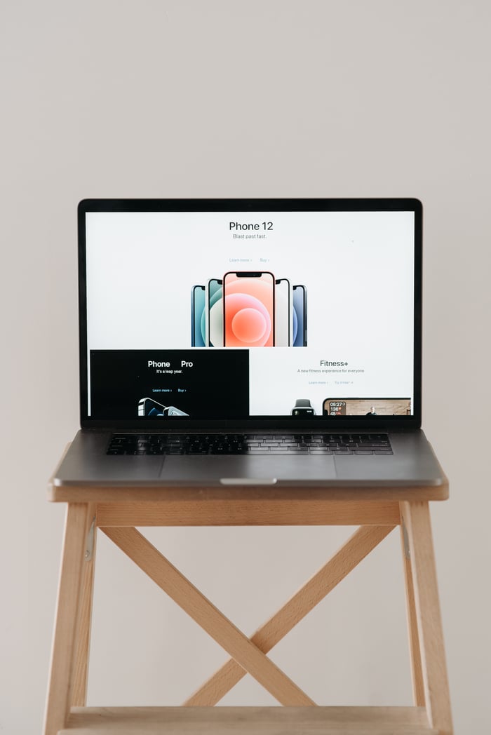 A sleek laptop on a wooden table showing a smartphone advertisement, perfect for tech and gadget content.